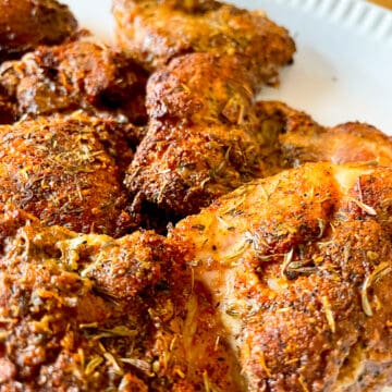 Crispy and juicy air fryer boneless skinless chicken thighs on a white serving platter