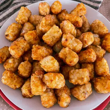 Crispy Air Fryer Tater Tots on a white plate atop a black and cream striped napkin