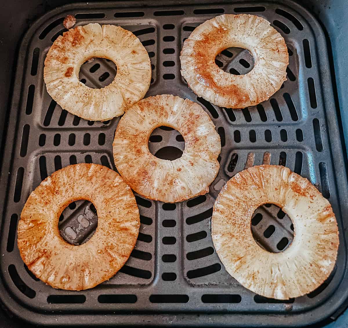 pineapple rings topped with brown sugar mixture in the basket of an airy fryer