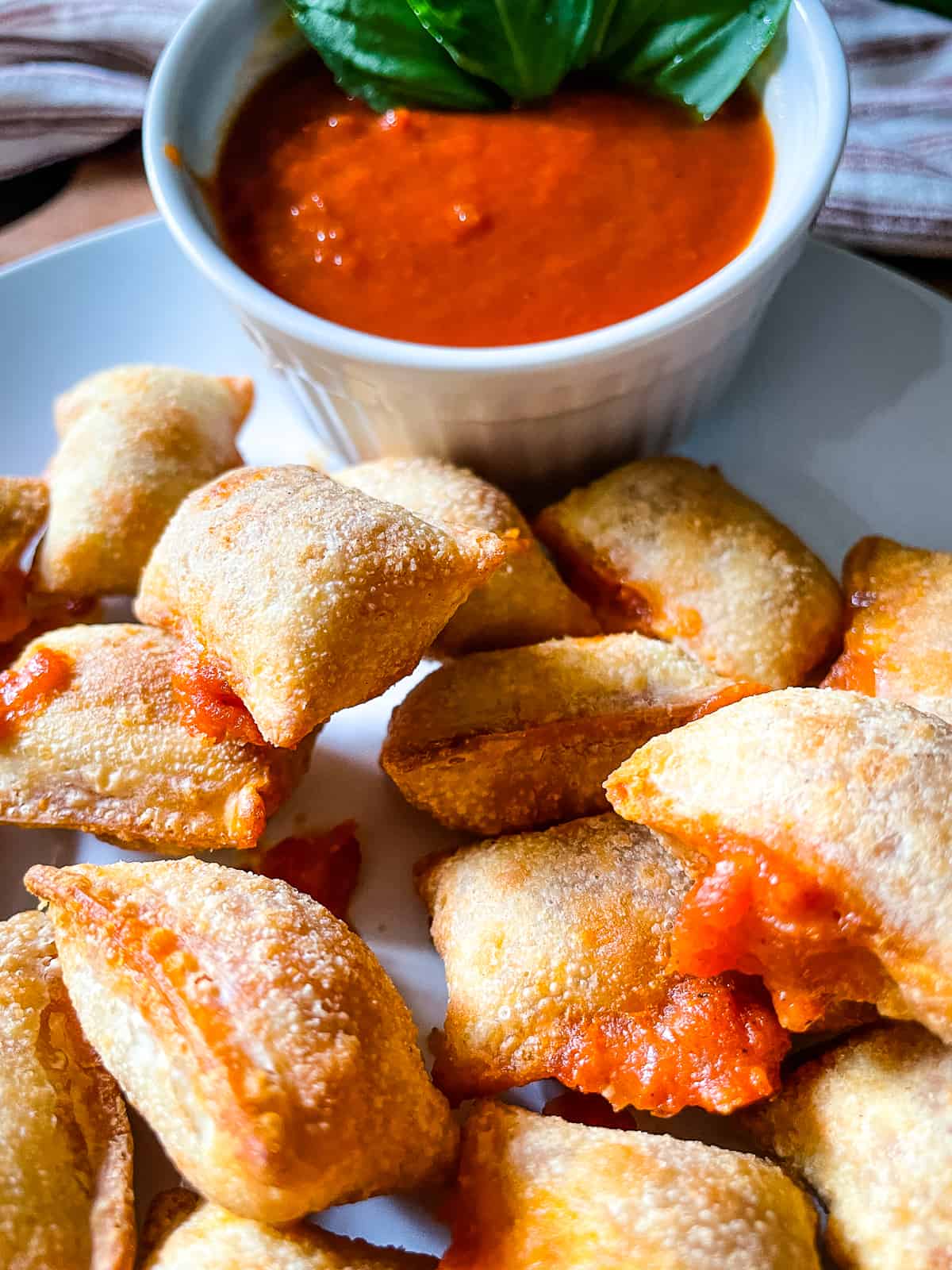 White plate with a pile of freshly made pizza rolls and marinara sauce for dipping