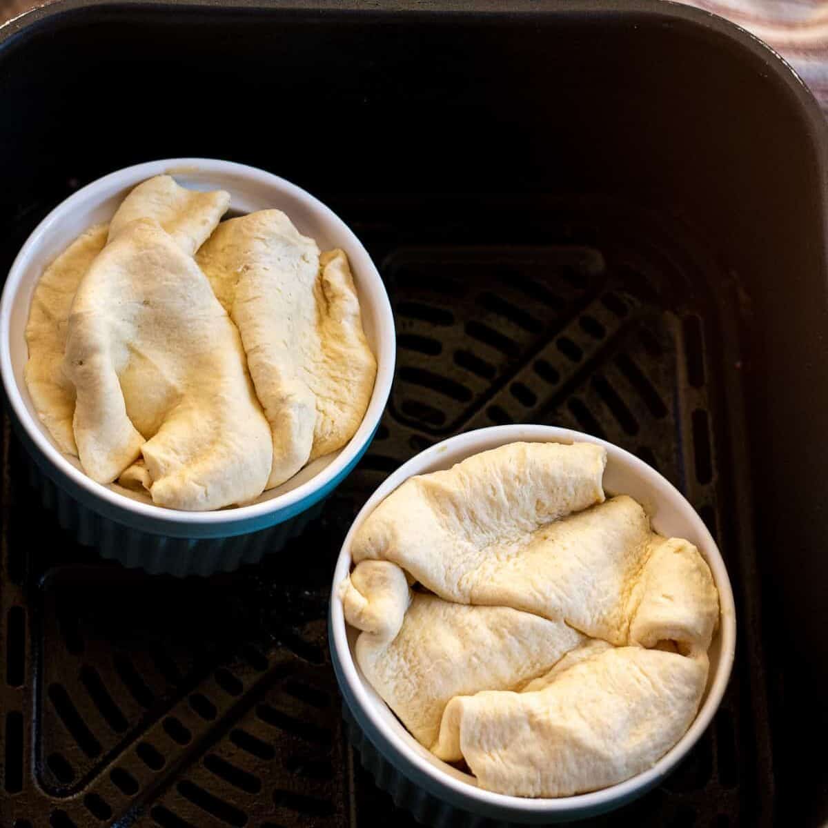 two ramekins filled with ham pot pies in an air fryer basket
